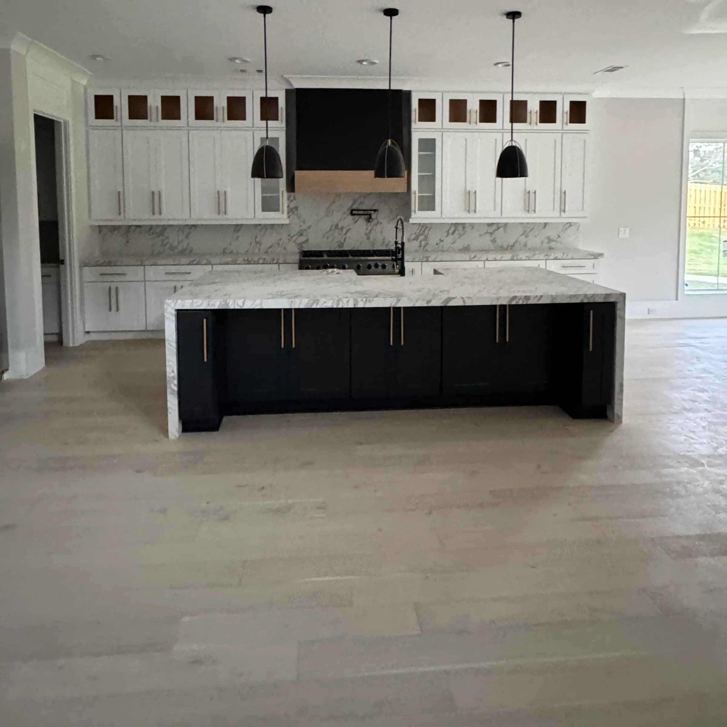 White inset cabinets to the ceiling, black island and dramatic marble slab backsplash