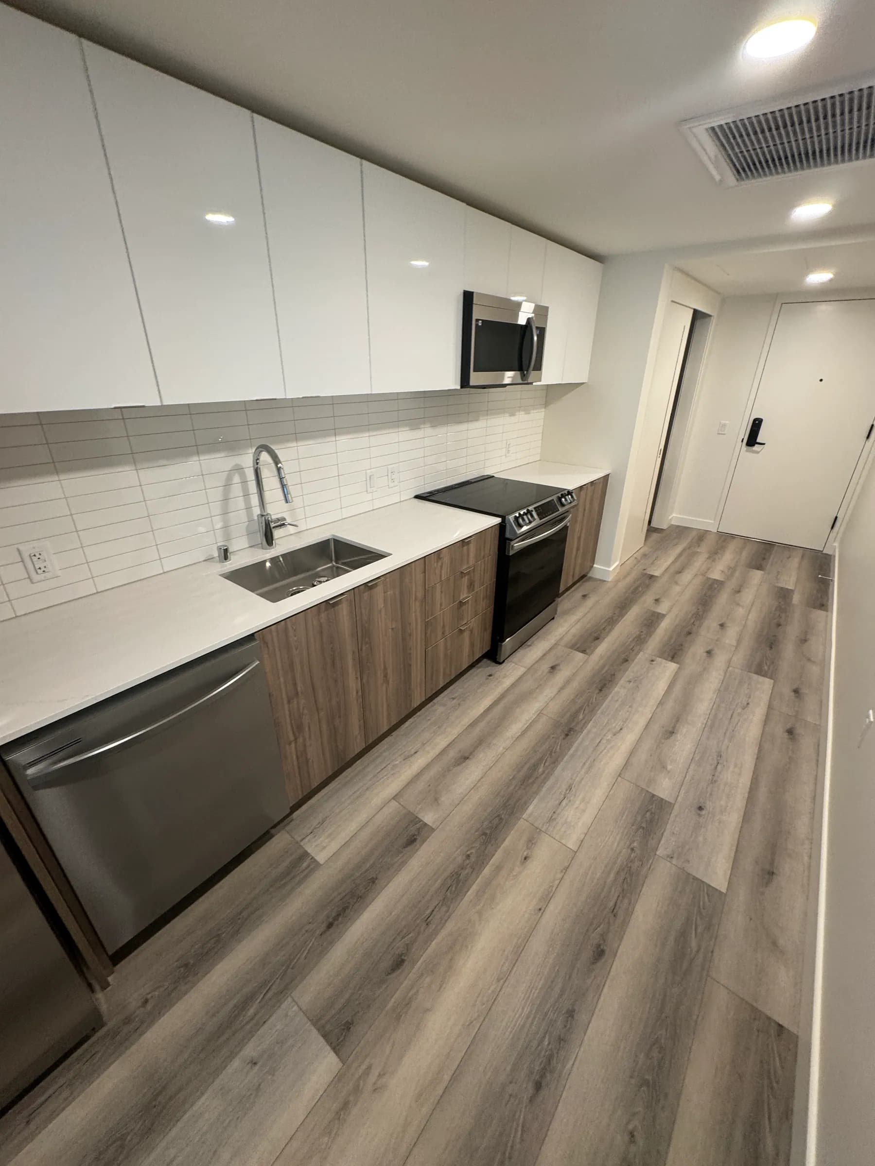 Compact galley kitchen with gloss white uppers and walnut flat-panel base cabinets
