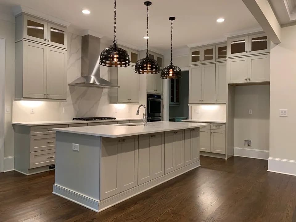 Greige cabinets with stainless chimney hood and marble backsplash
