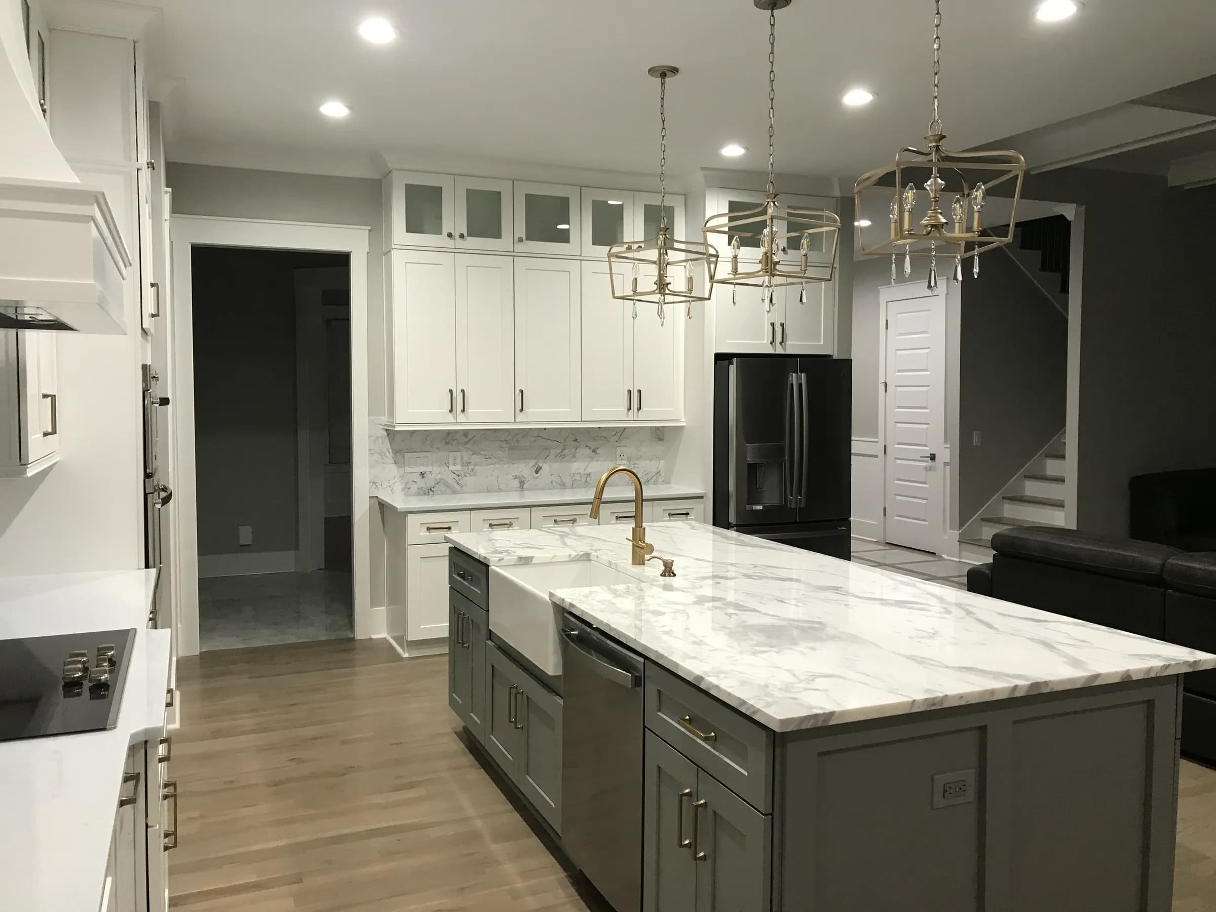 White uppers, grey island, marble waterfall counter, brass lantern pendants and farmhouse sink