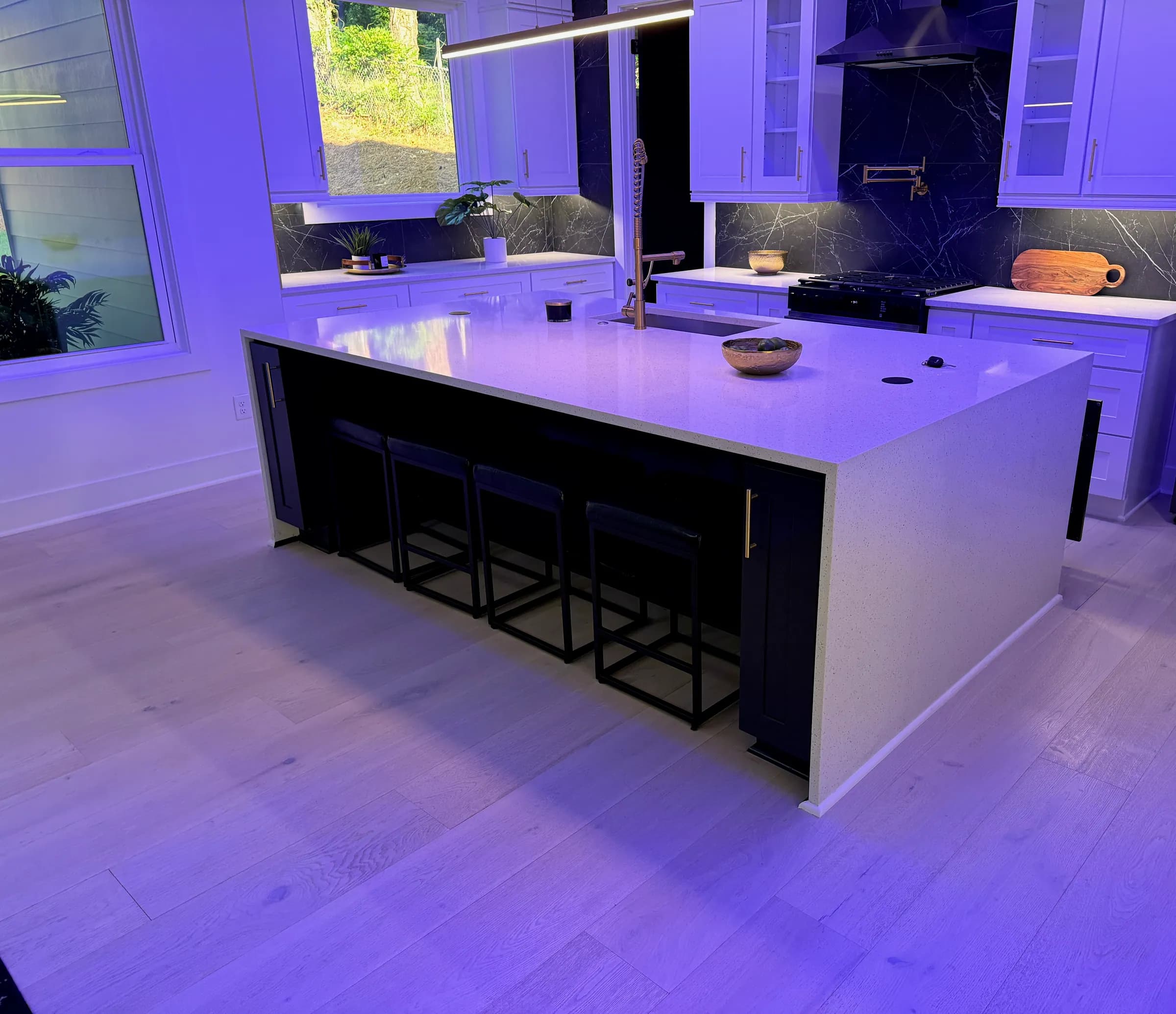 Navy island with waterfall quartz beneath a blue LED tray ceiling