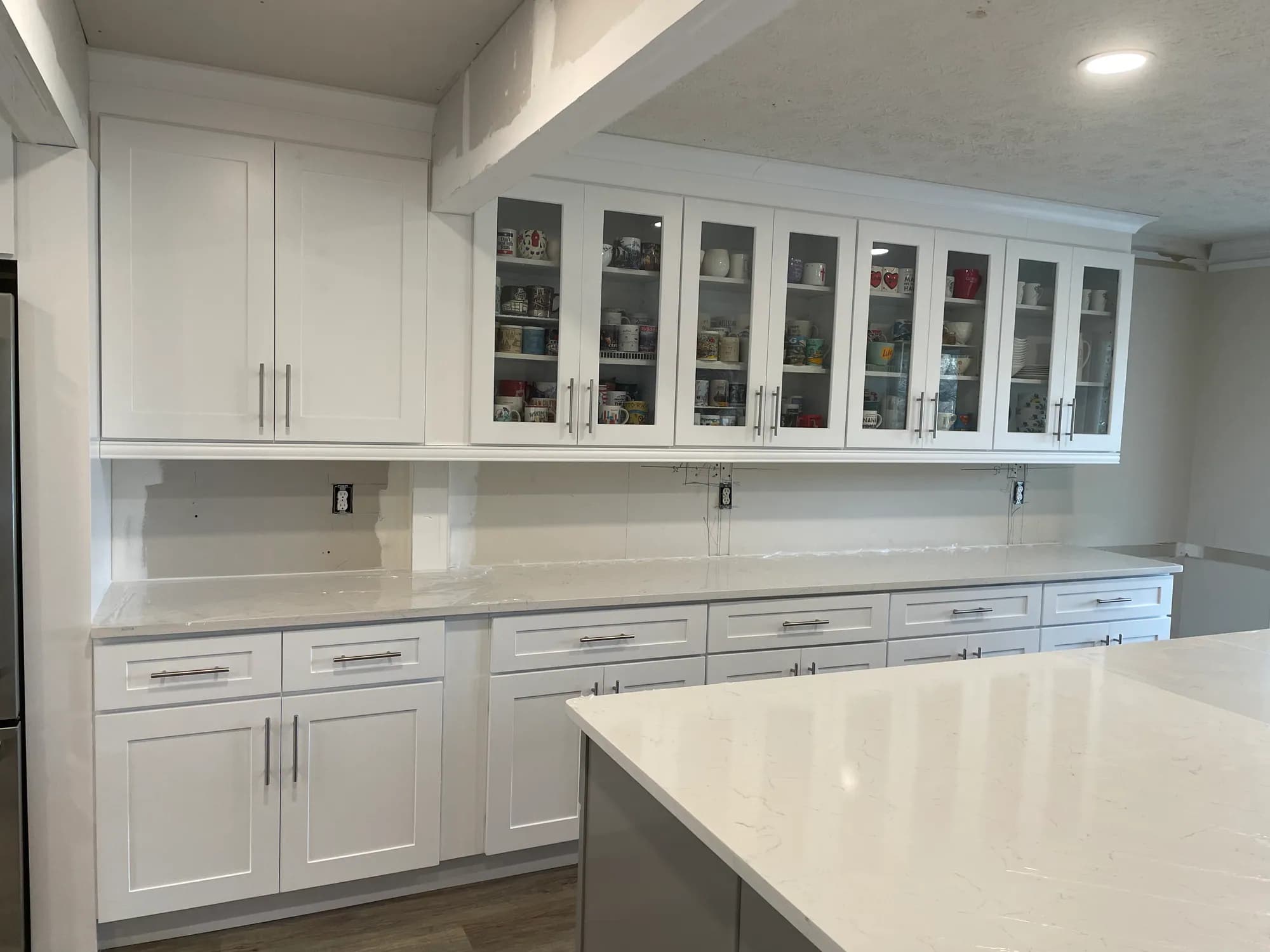 Glass-front upper cabinets installed, backsplash still to come