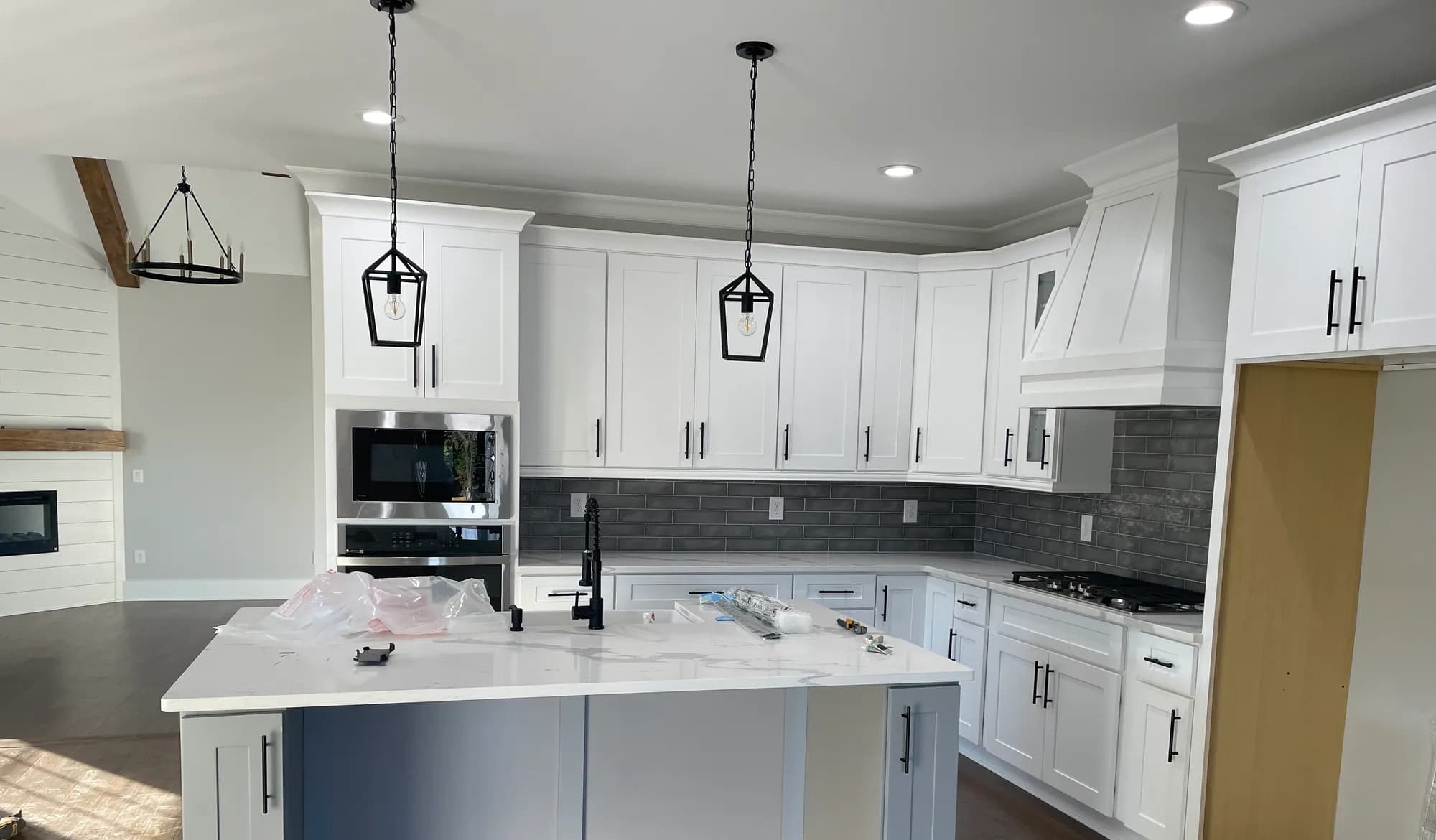 White shaker kitchen with grey subway backsplash and black hardware mid-install