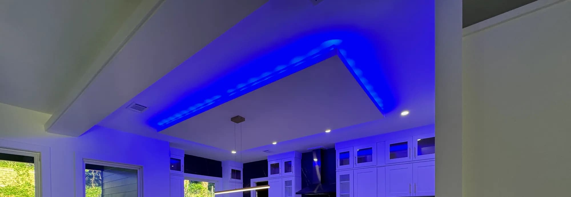 Blue LED cove lighting above white uppers and a black marble backsplash